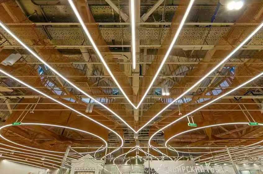 V-shaped curved LED linear lights converging in airport terminal